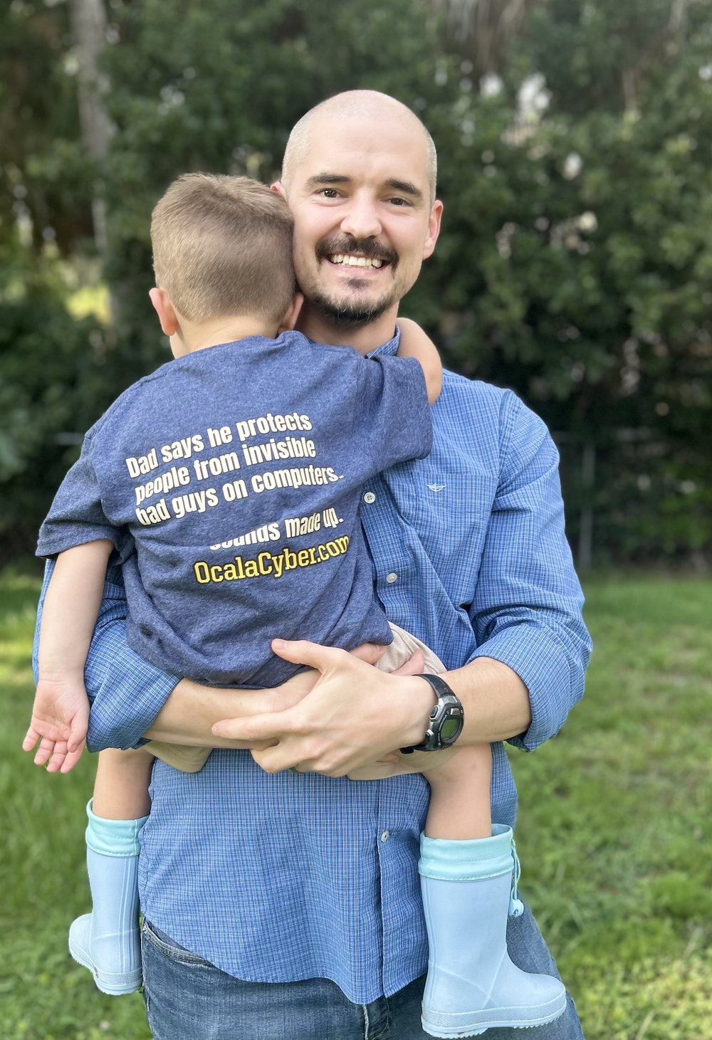 Sidney 'Seth' Wilson, founder of Ocala Cyber, holding his young son